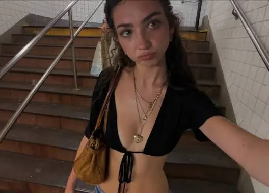 Eliza Browne in a public outfit-video preview beside a staircase.